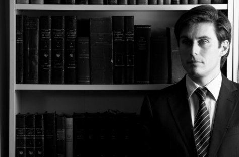 Zwart-wit portret van een man in pak voor een boekenkast