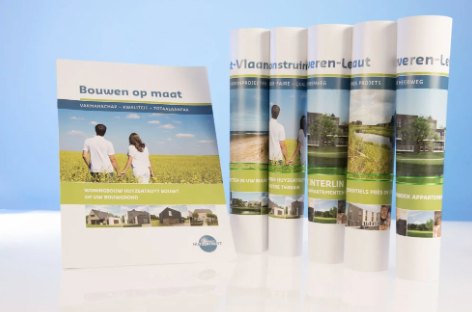 Brochures van een bouwbedrijf op een witte tafel tegen blauwe achtergrond